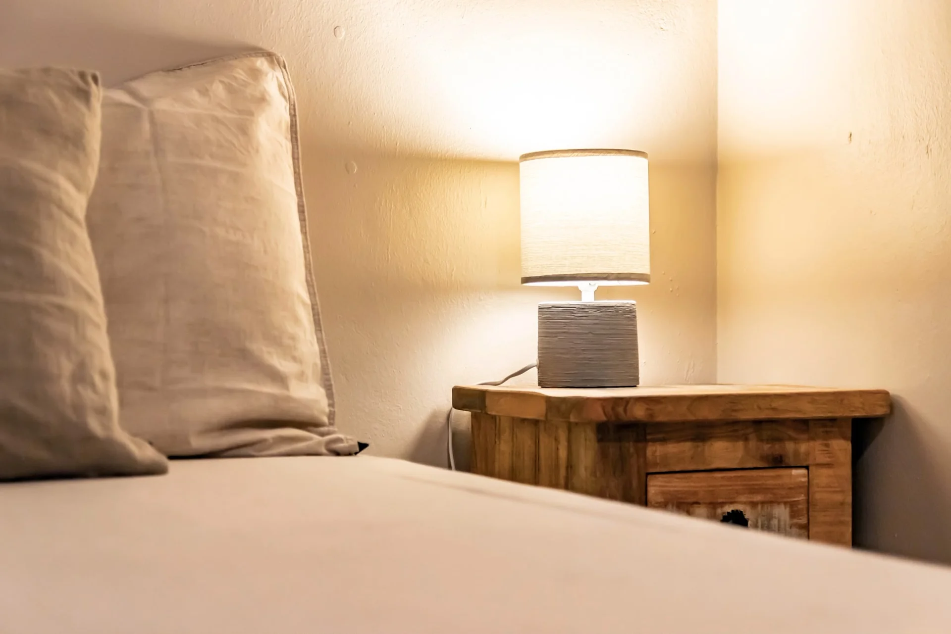 Sfeervol houten nachtkastje met lamp in Appartement Saars