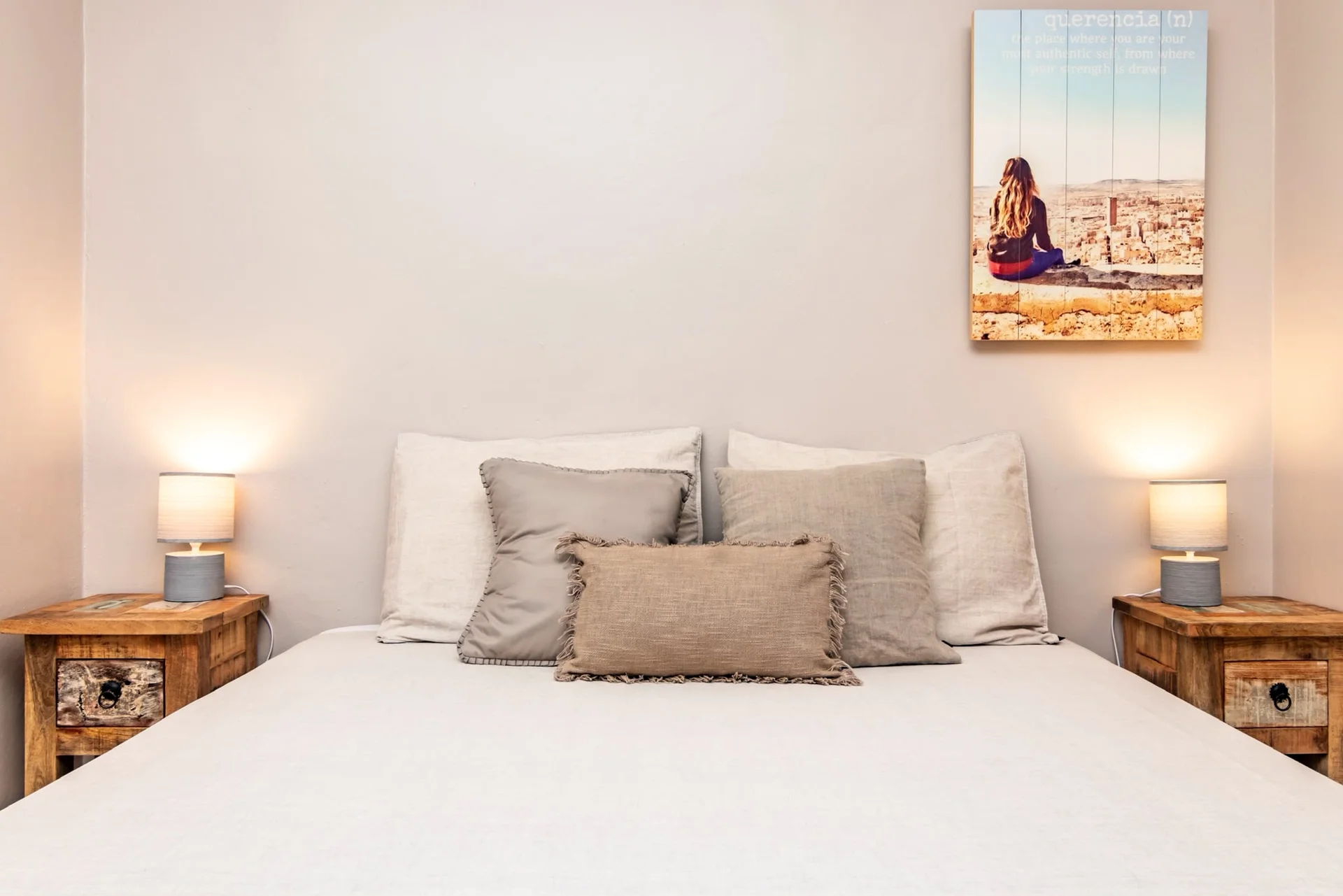 Bed met linnen kussens en houten nachtkastjes in Appartement Saars